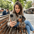 Woman taking a selfie with a dachshund on a bench in an outdoor setting